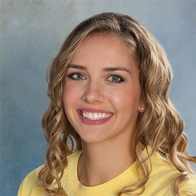 Young Woman Smiling By Green Wall