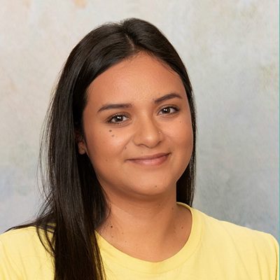 Young Woman Smiling By Green Wall
